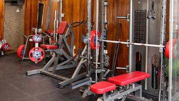 Uma academia com equipamentos de musculação, um ventilador de teto e paredes de madeira.