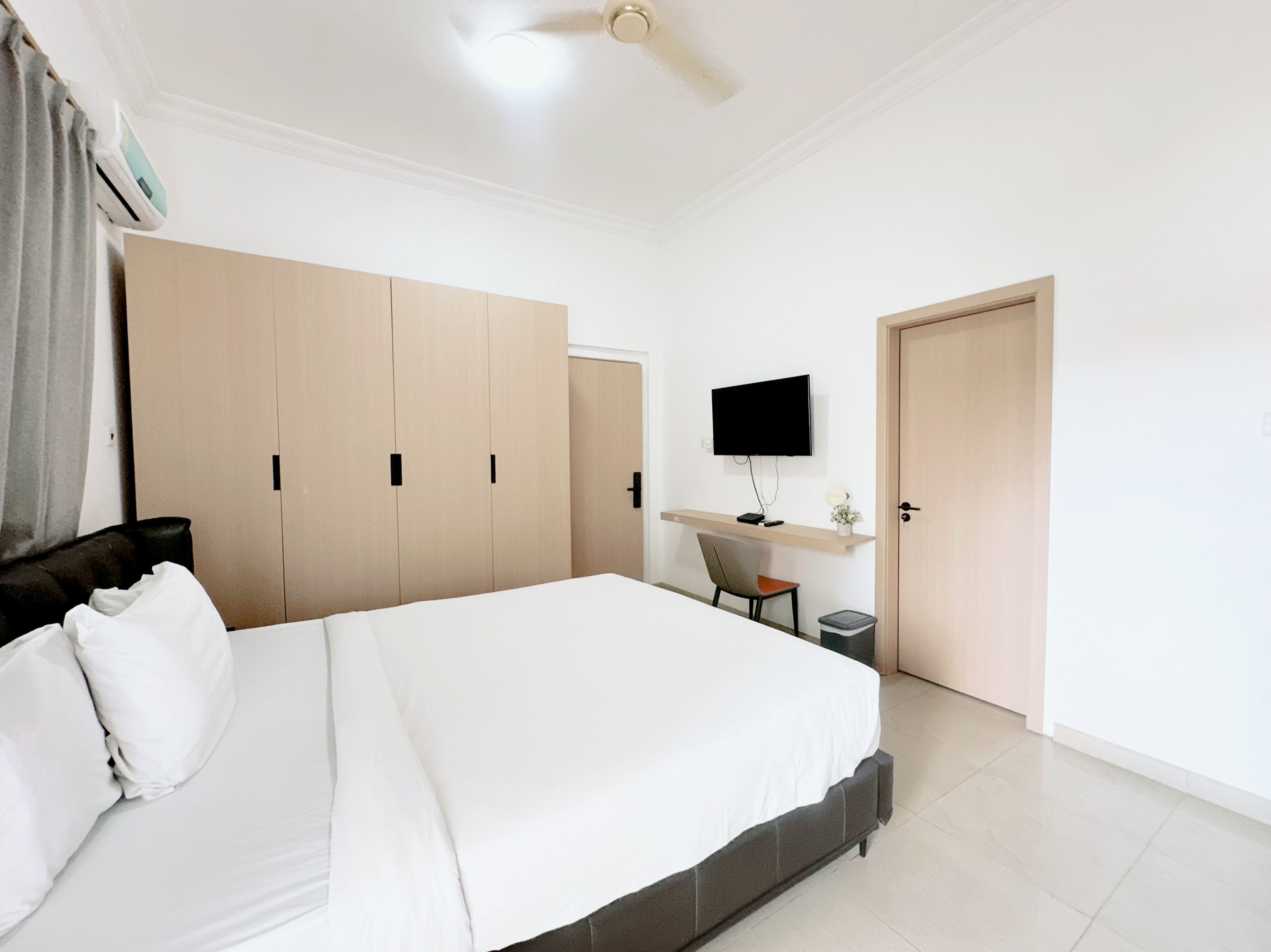 Ein Schlafzimmer mit Bett, Schreibtisch, Stuhl, Fernseher und Kleiderschrank.
