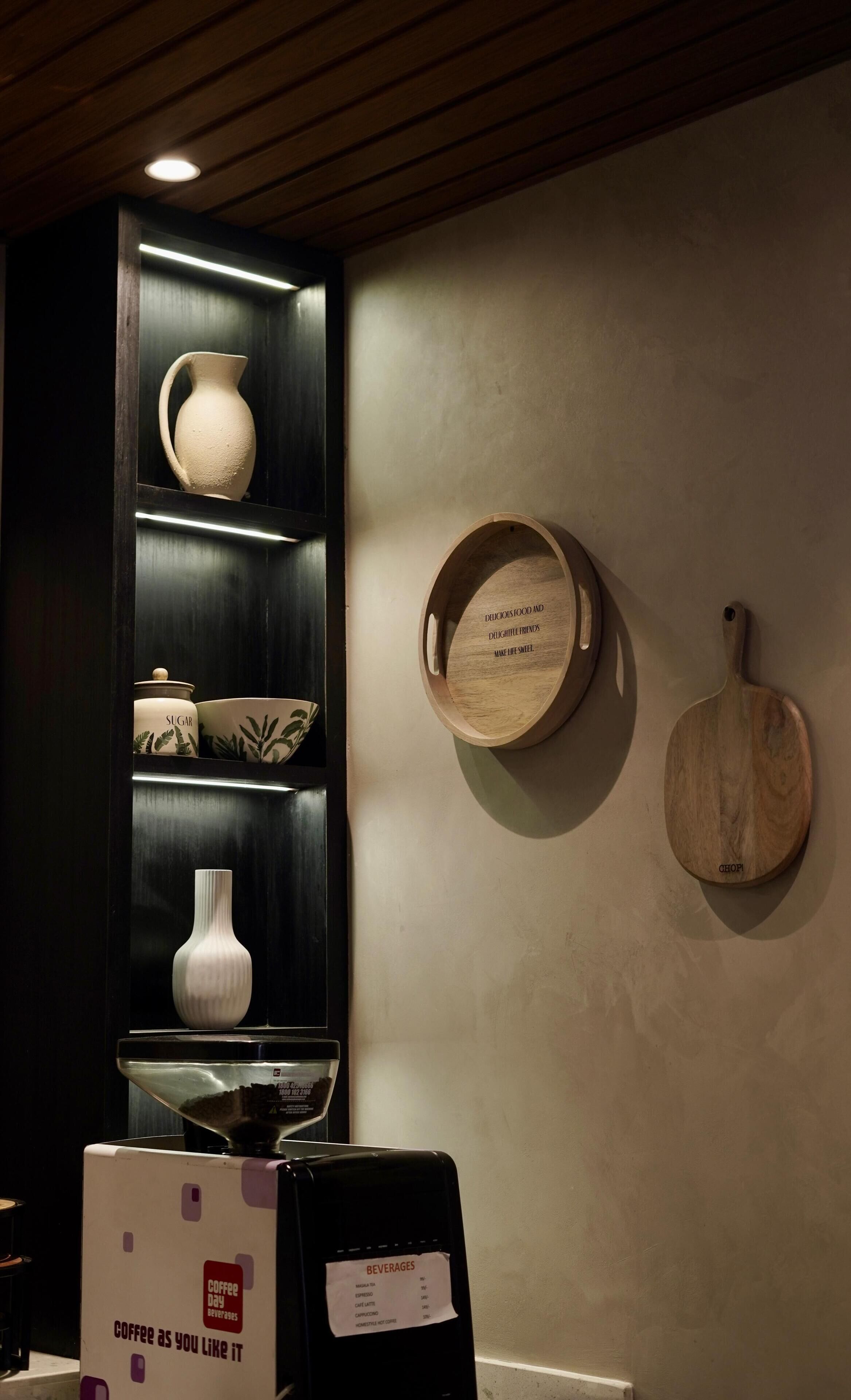 A kitchen area with a coffee machine, a sign for coffee beverages, and a wooden wall-mounted board with text.