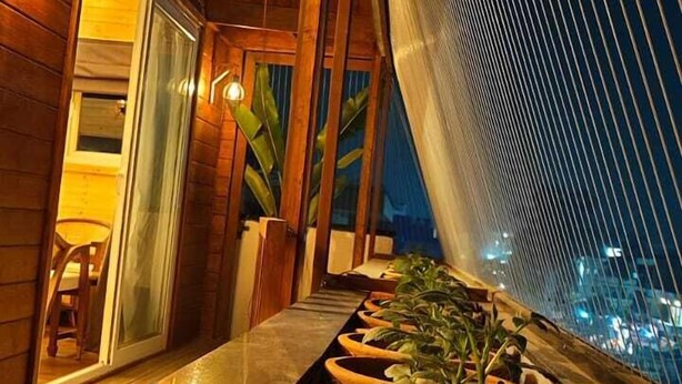 A rooftop terrace with potted plants, wooden beams, and a view of the city at night. - Narayan kothi (Varanasi)