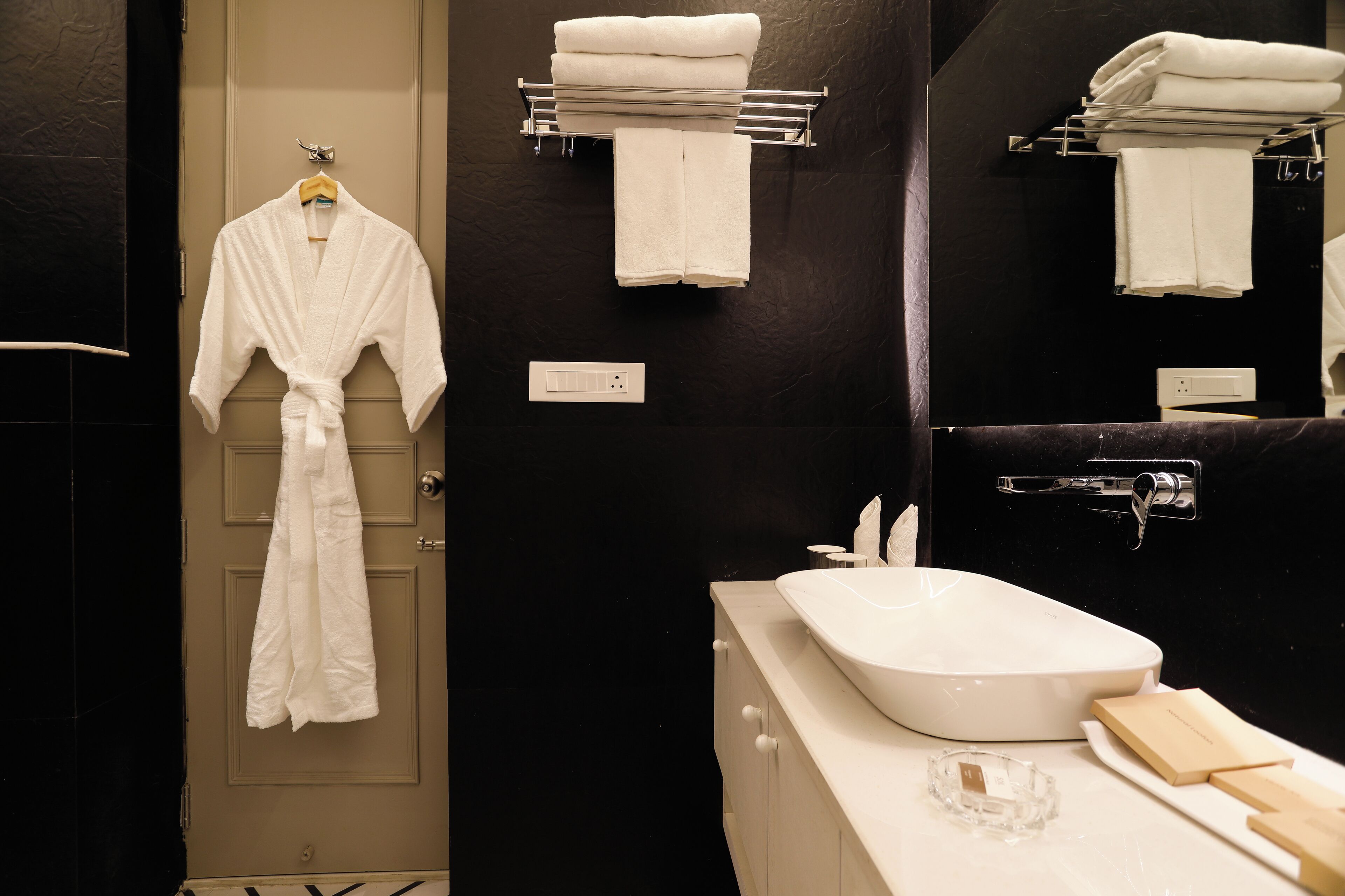 A bathroom with a white sink, a mirror, and a towel rack with folded towels.