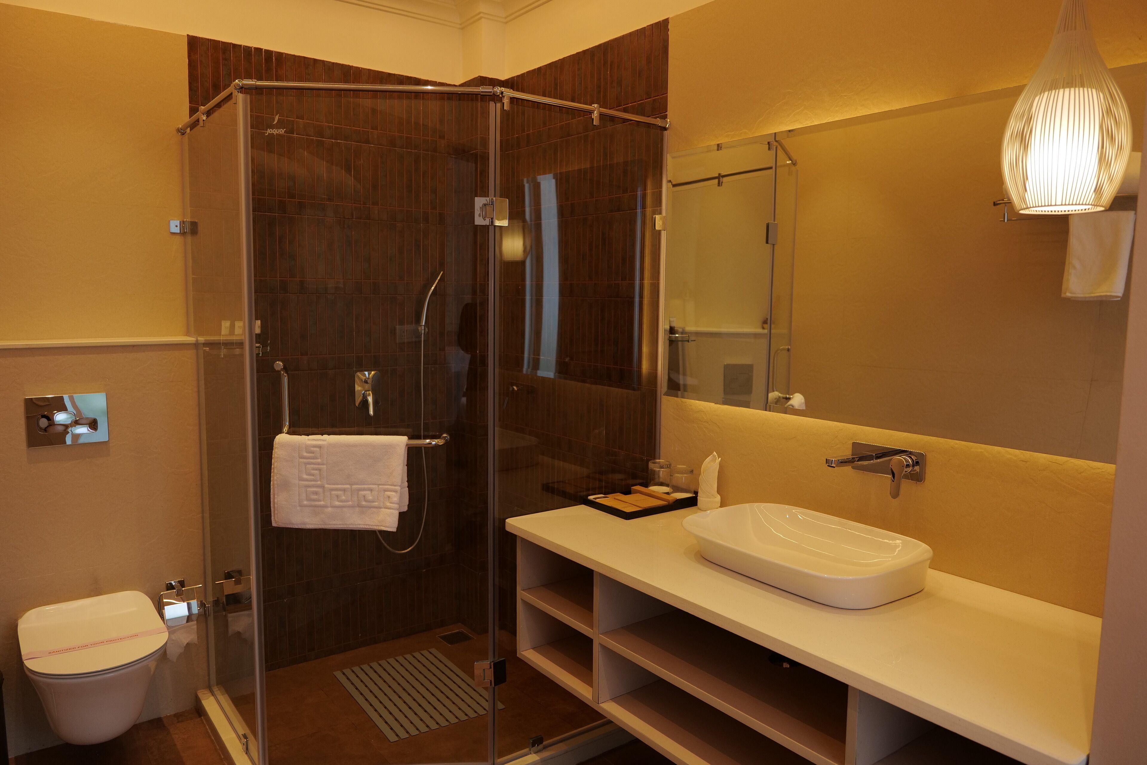 A modern bathroom with a glass-enclosed shower, a white sink, and a large mirror.