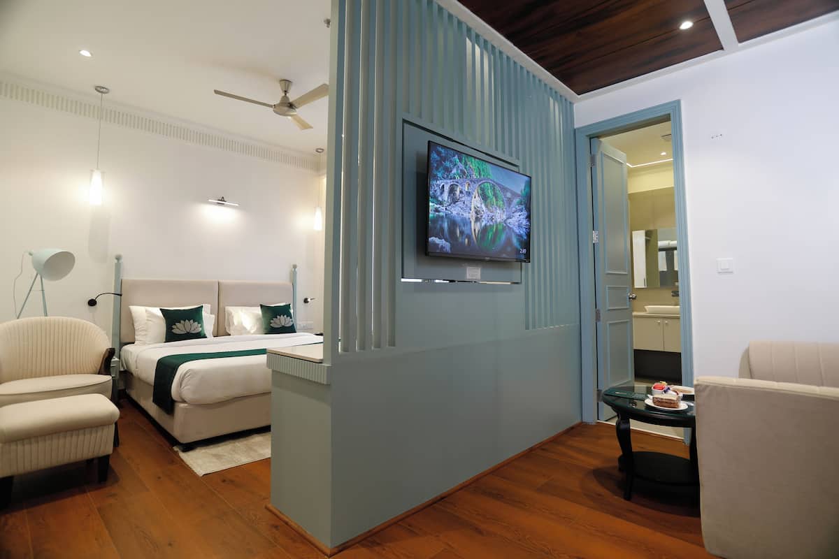 A modern bedroom with a bed, a chair, a TV, and a small table with a cake.