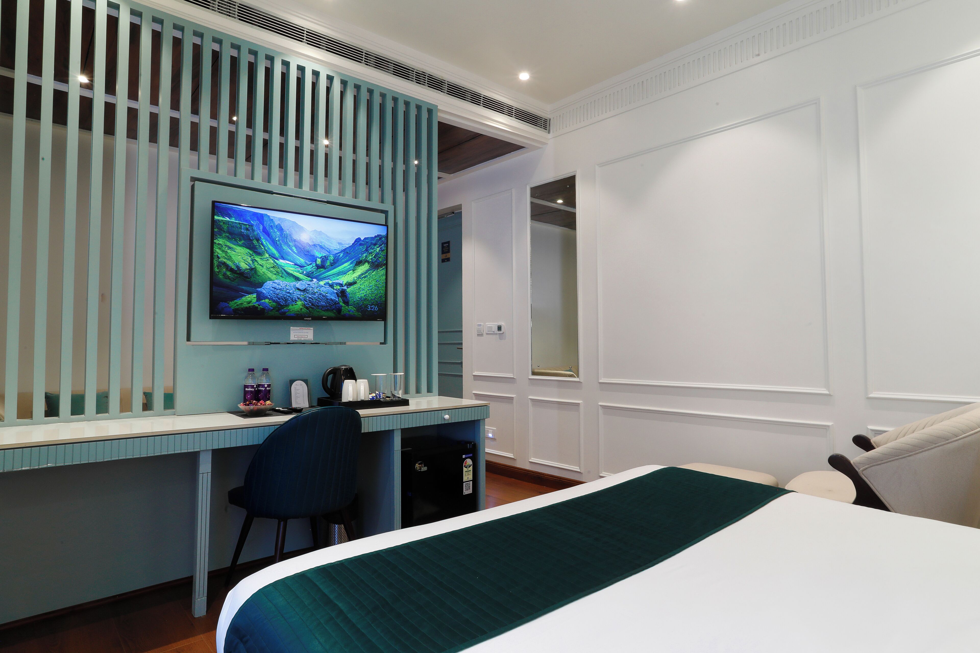 Habitación de hotel con cama, escritorio con computadora, televisor y silla.