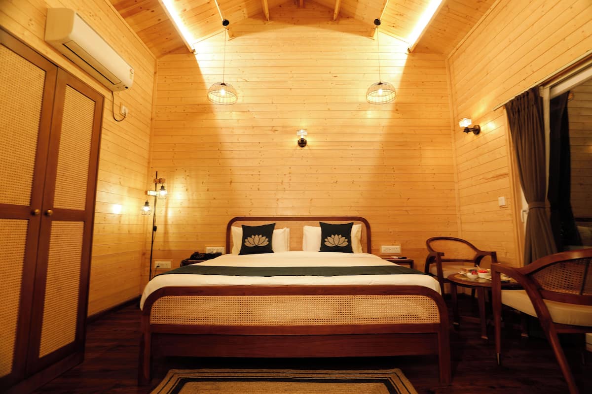 A wooden-paneled bedroom with a bed, bedside tables, and a chair.