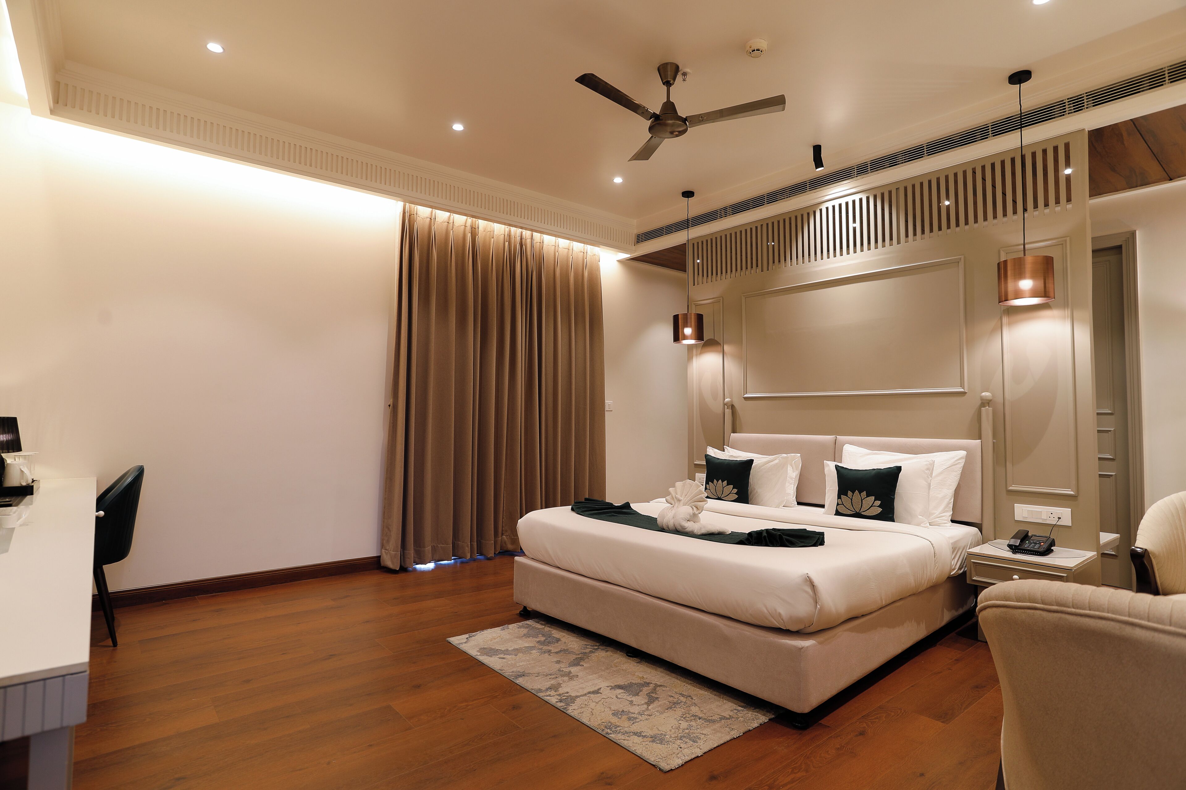 A modern hotel room with a large bed, a desk, and a chair.