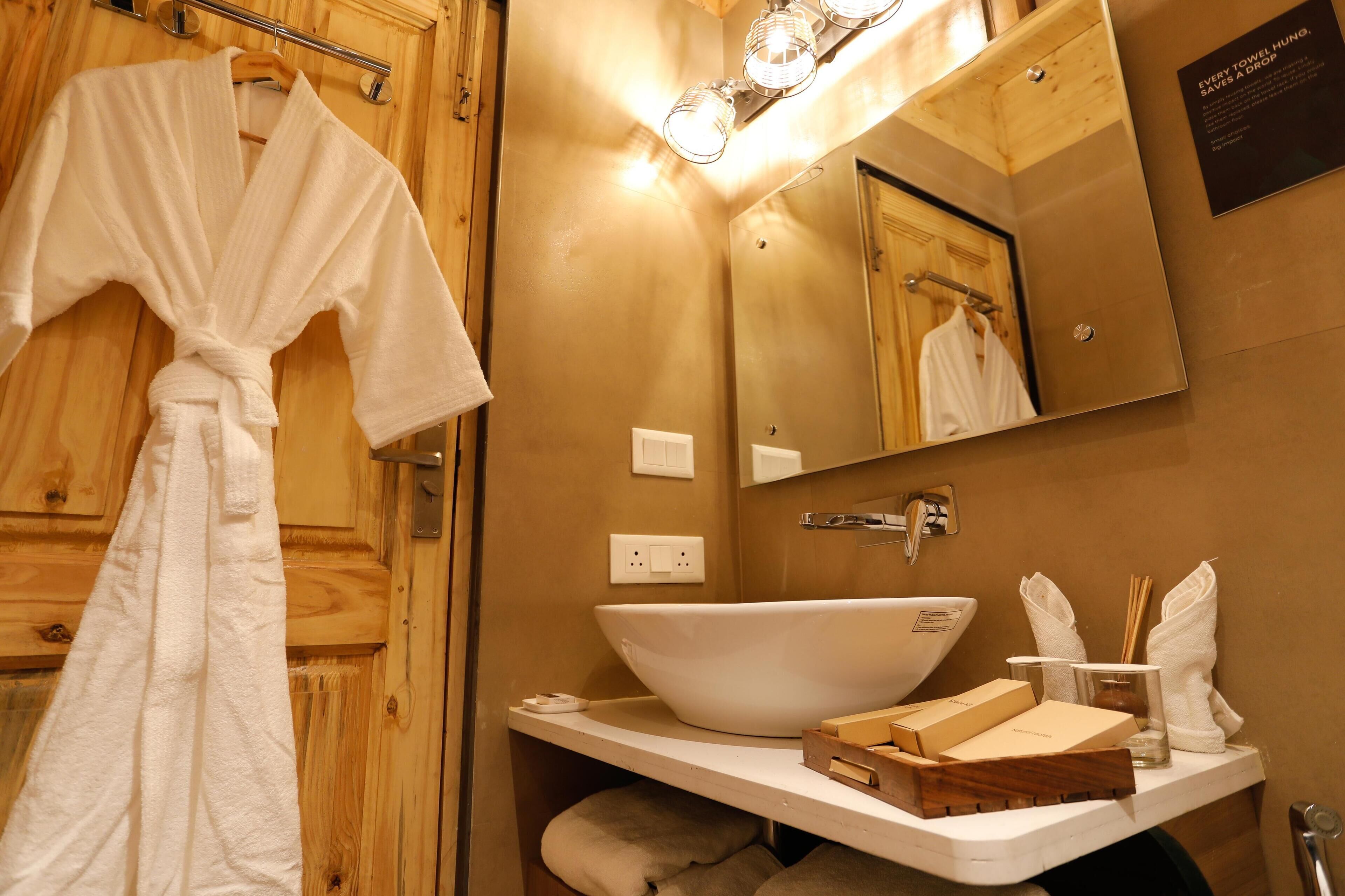 Ein Badezimmer mit Holztür, einer weißen Badewanne, einem Waschbecken mit Toilettenartikeln und einem Handtuchhalter.