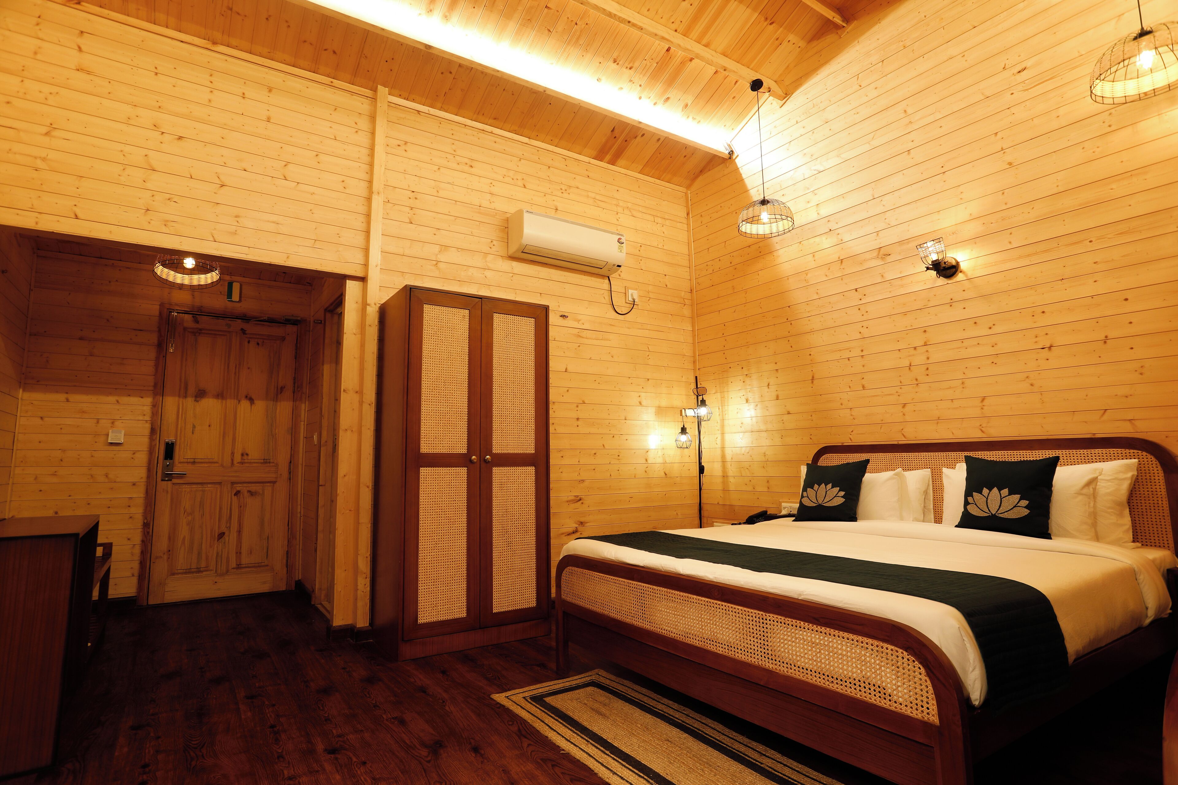 A wooden-paneled room with a bed, a desk, and a door.