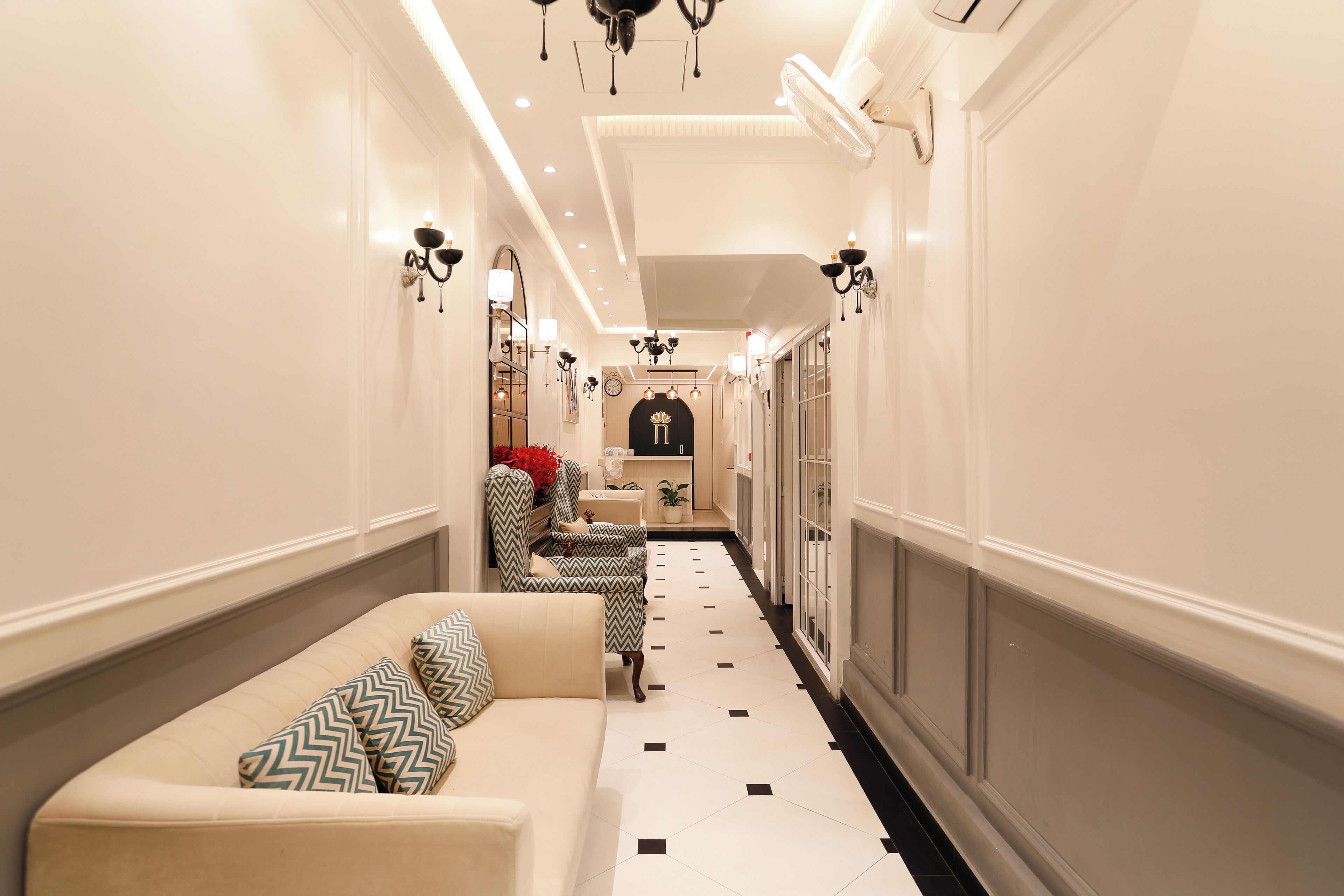 A hallway with a sofa, armchair, and a small table with a plant.