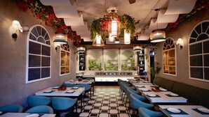 A restaurant with a checkered floor, blue chairs, and tables set for dining. - Narayan kothi (Varanasi)