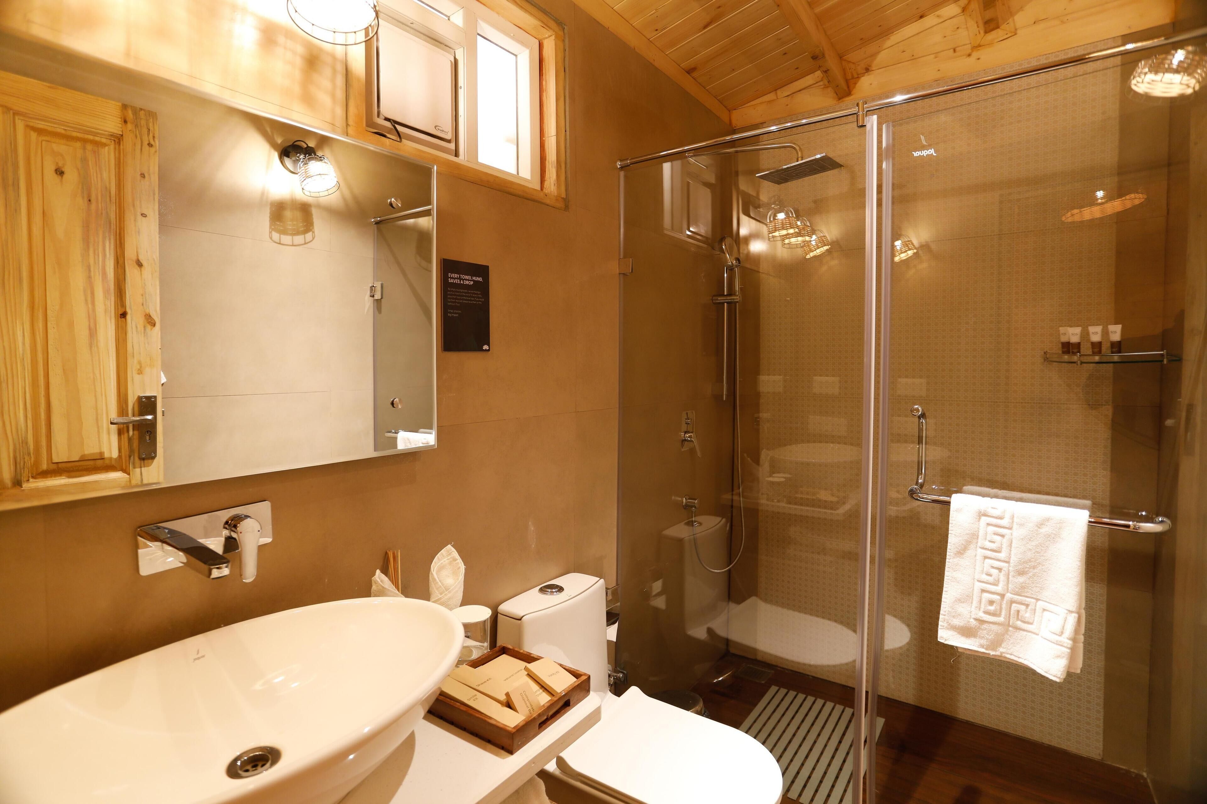 A bathroom with a wooden ceiling, a glass shower enclosure, a sink, and a toilet.