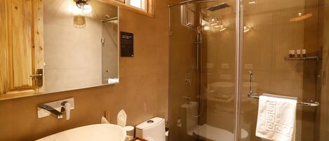 A bathroom with a wooden ceiling, a glass shower enclosure, a sink, and a toilet.