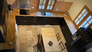 Uma cozinha com mesa de madeira, armários escuros e parede de tijolos.
