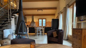 Uma sala de estar aconchegante com lareira, um espaço de refeições e uma escada.