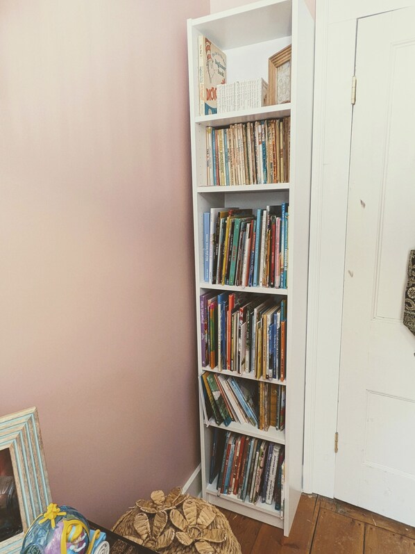 Una estantería llena de libros, un cuadro enmarcado y un globo decorativo.
