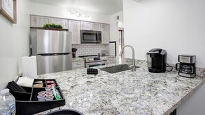 Una cocina moderna con electrodomésticos de acero inoxidable, encimera de granito y cafetera.