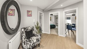 A modern living room with a large mirror, a patterned sofa, and a dining area with chairs and a table. - Buzzing Brighton Apartments | By My Getaways (Brighton)