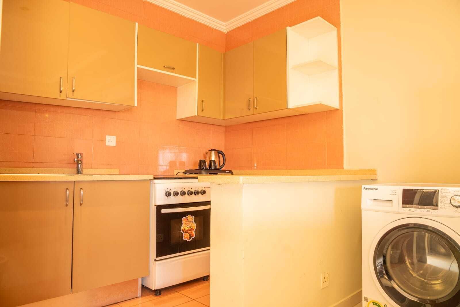A compact kitchen with wooden cabinets, a stove, and a washing machine.