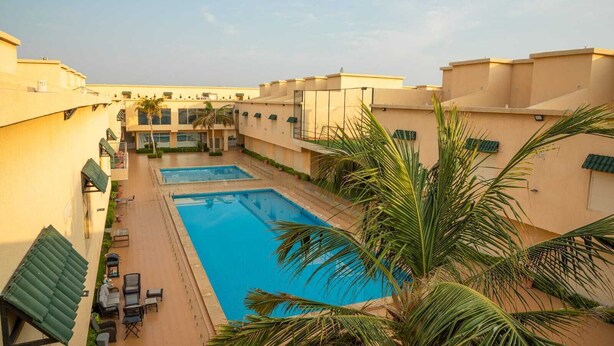 Un área de piscina con dos piscinas rectangulares, rodeada de edificios con balcones y palmeras.