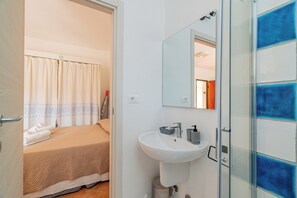 A hotel room with a bed, a bathroom with a sink, and a shower area.