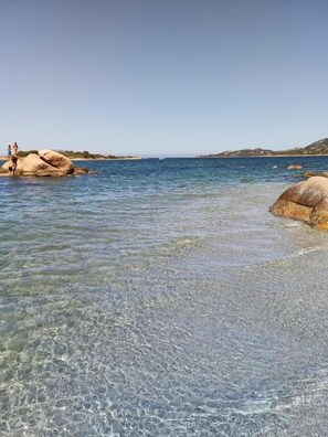 A clear coastal area with large rocks and calm water.