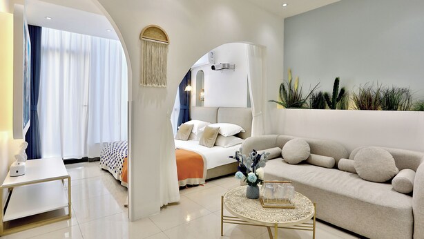 A modern hotel room with a bed, sofa, and a small round table with a vase. - Shanghai Yinxubai Designer Homestay  (Shanghai)