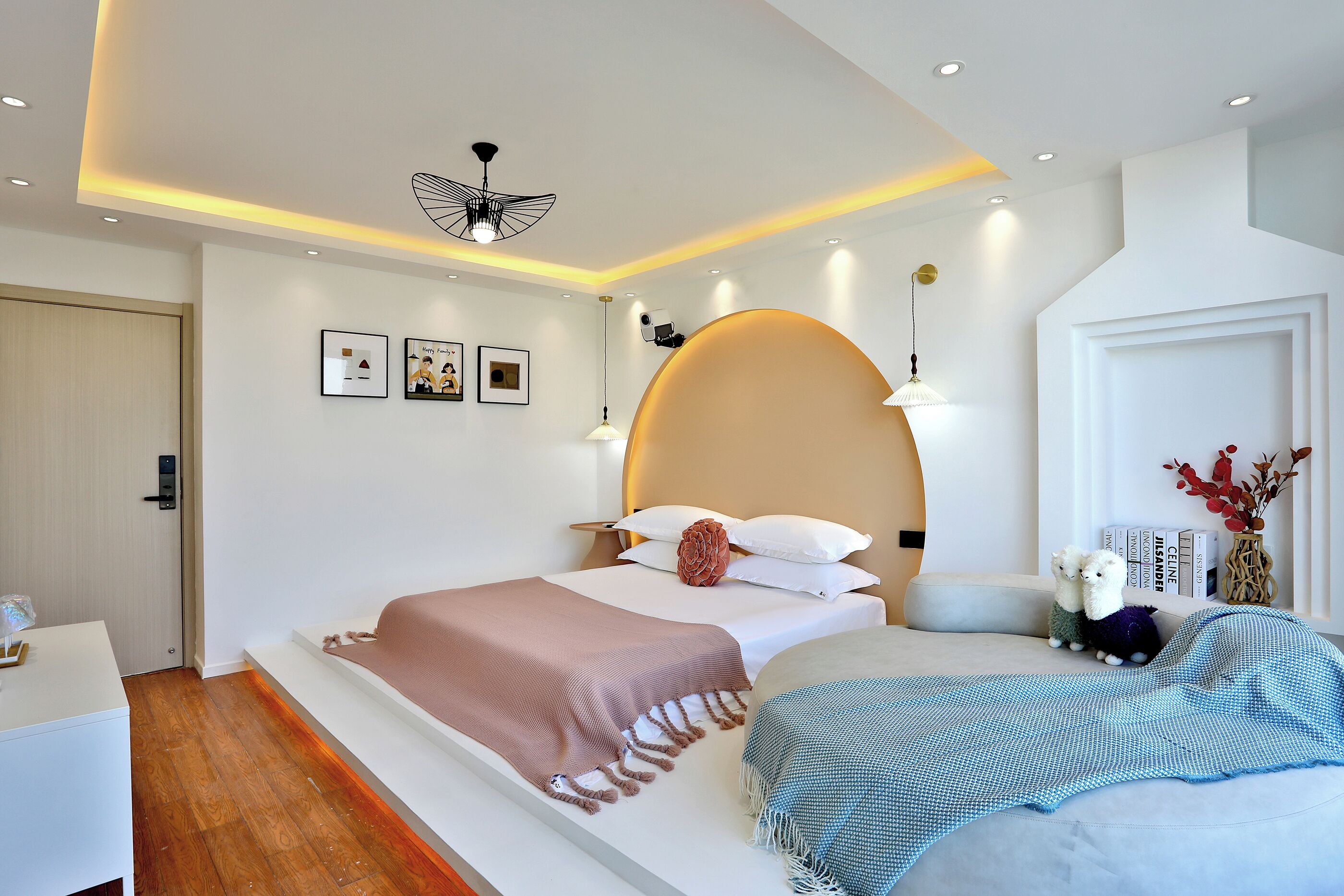 A modern bedroom with a large bed, bedside tables, a ceiling light, wall-mounted artwork, and a decorative vase.