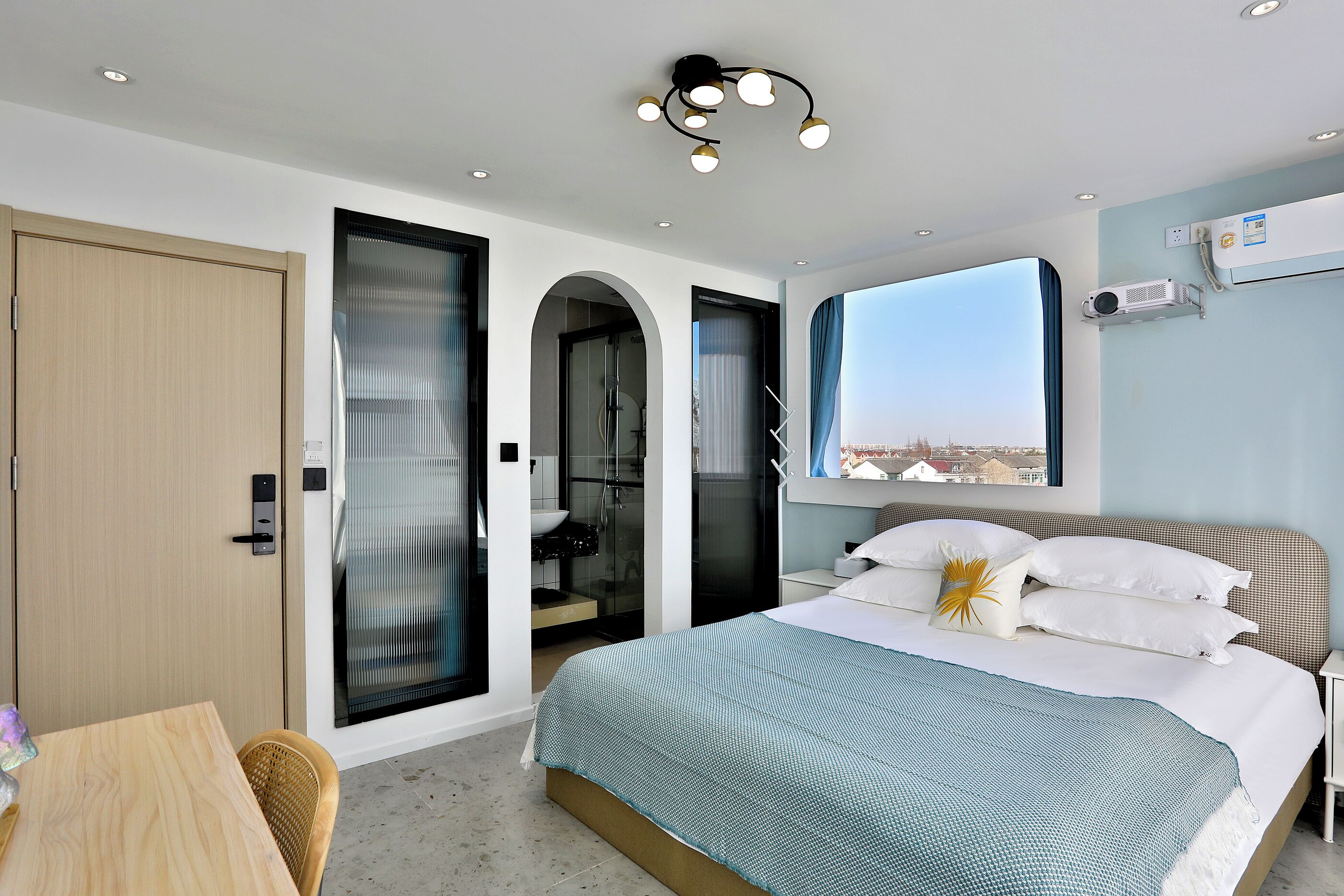 A modern bedroom with a large bed, a view of the city, and a sliding door leading to a bathroom.