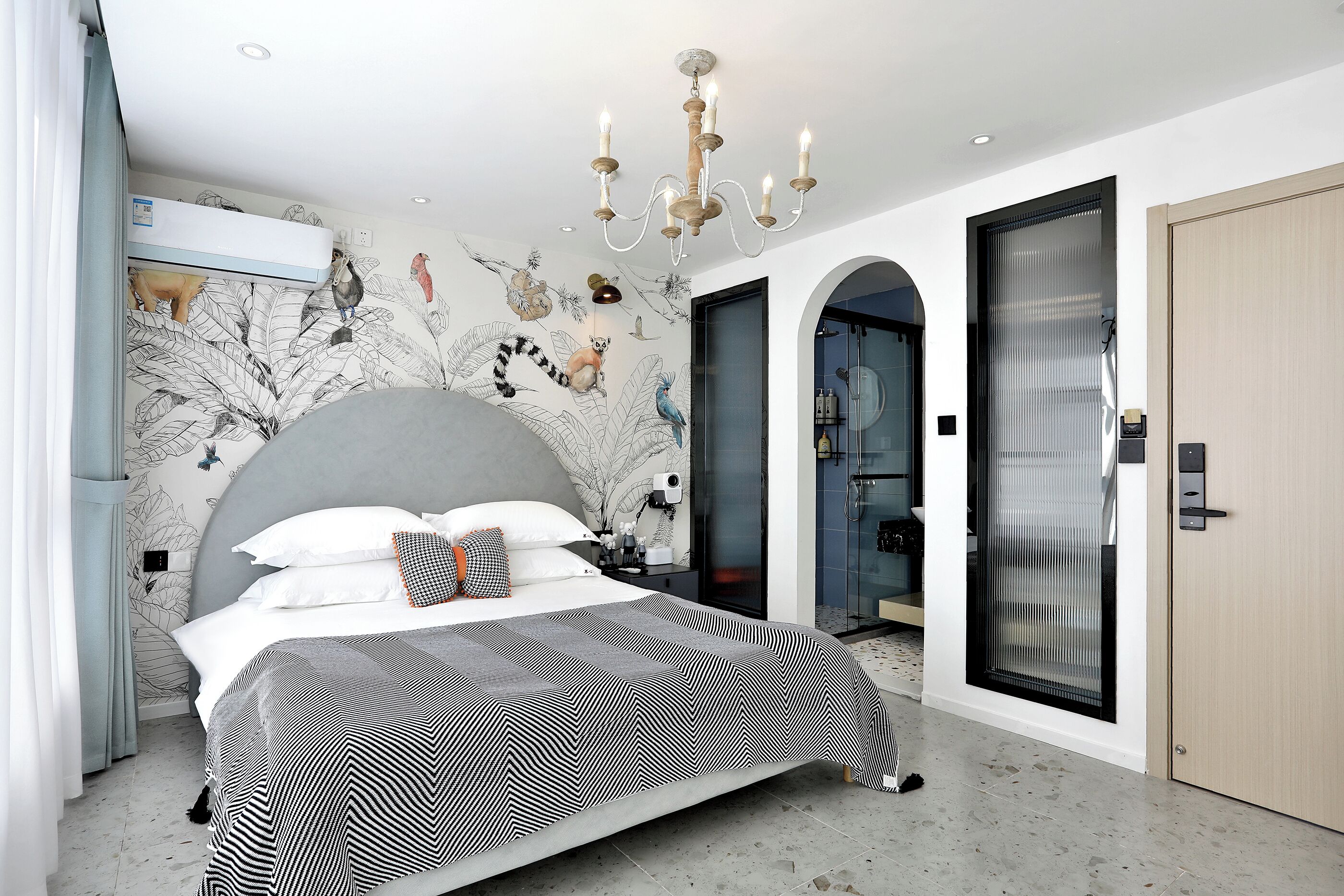 A modern bedroom with a large bed, a chandelier, and a mural on the wall.