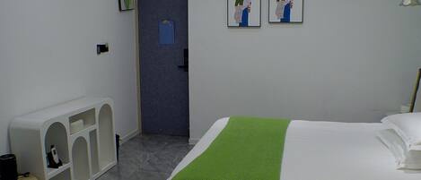 Une chambre d’hôtel comprenant un lit, un petit coin salon et une porte donnant sur une autre pièce.