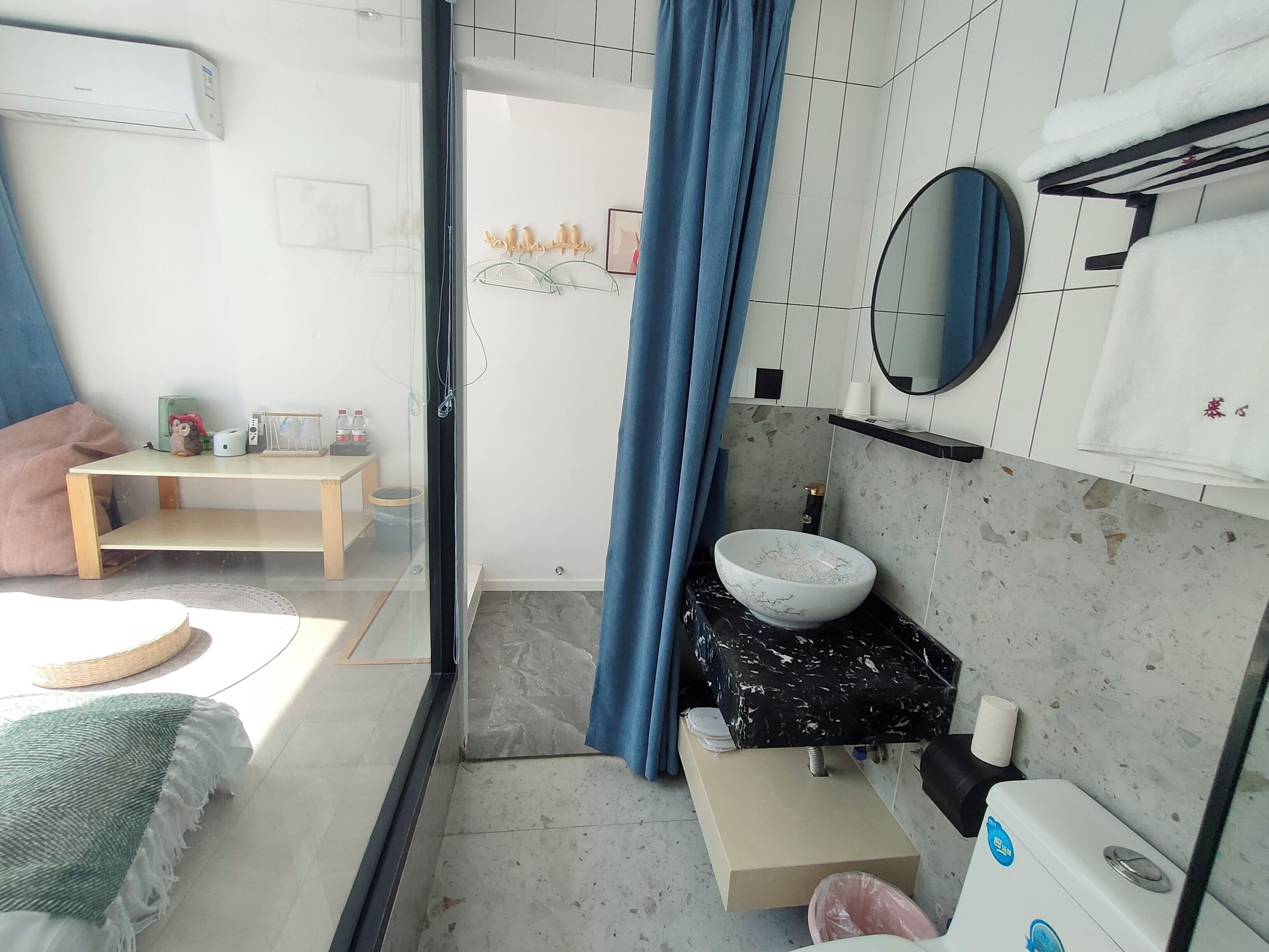 Een moderne badkamer met een wit wastafelmeubel, een zwart aanrecht en een blauw douchegordijn.