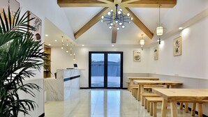 A spacious interior with a reception desk, wooden tables, and a large window with a view. - Shanghai Yinxubai Designer Homestay  (Shanghai)