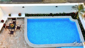 A swimming pool with a stone deck, surrounded by potted plants and flowers. - Shanghai Yinxubai Designer Homestay  (Shanghai)
