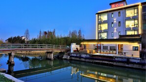 A modern building with a sign in Chinese characters, a bridge over a calm water body, and a reflection of the building in the water. - Shanghai Yinxubai Designer Homestay  (Shanghai)