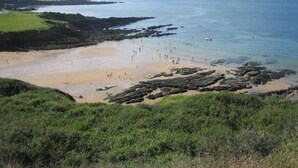 Une plage côtière avec des affleurements rocheux et une rive sablonneuse.