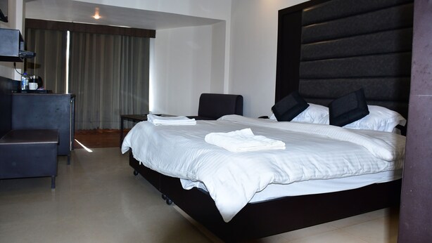 A modern hotel room with a large bed, a desk, and a chair. - HOTEL TRIDEV  (Reasi)