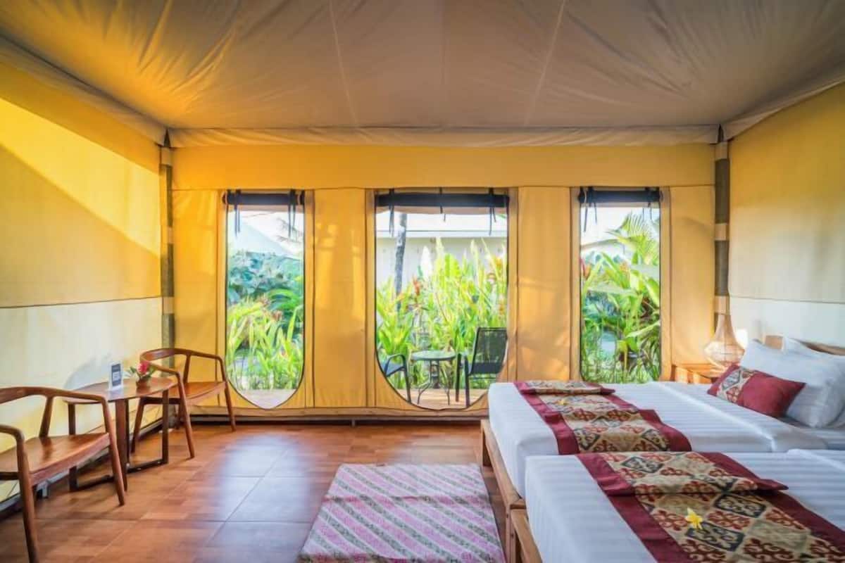 Una habitación tipo tienda de campaña con una cama, una silla y una mesa.
