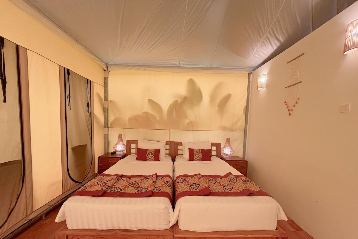 Una habitación con dos camas, un ventanal grande y una pared con diseño decorativo.