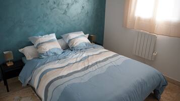 A bedroom with a bed, a nightstand, a lamp, and a window with curtains.
