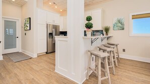 Eine moderne Küche mit weißen Schränken, einem Edelstahlkühlschrank und Holzstühlen.