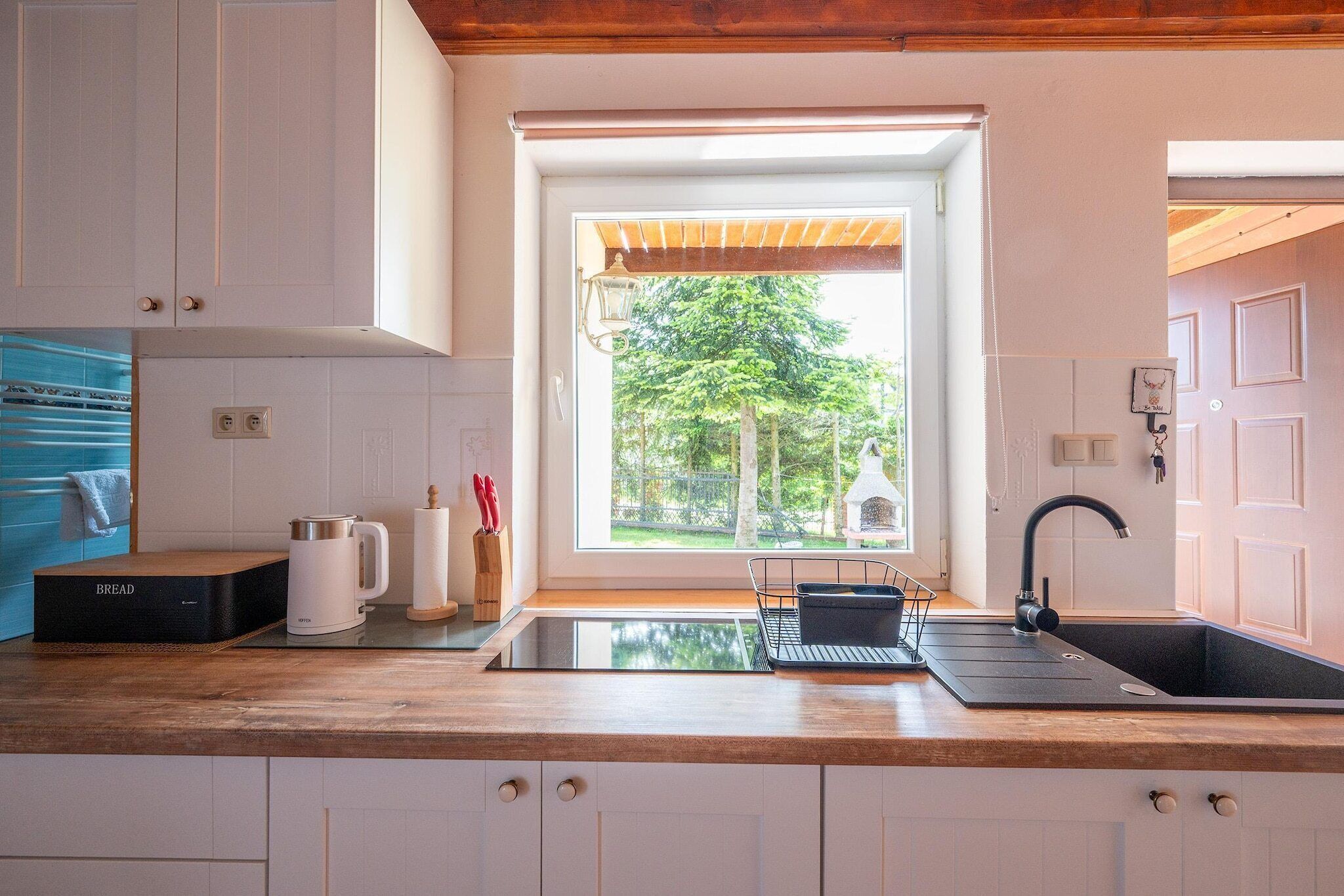 Uma cozinha moderna com forno embutido, pia e janela com vista para um jardim.
