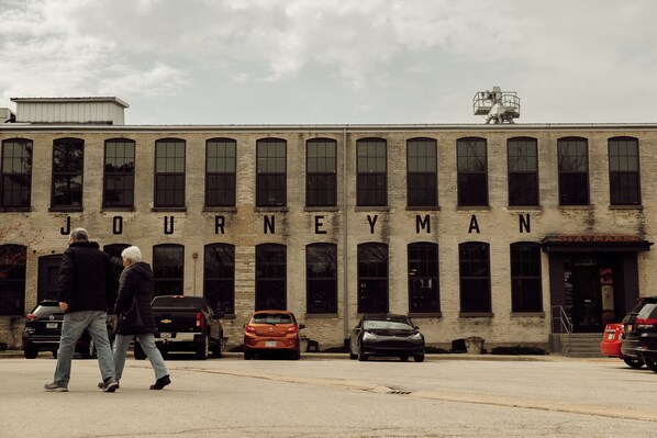 A building with the name "JOURNEYMAN" on the facade, featuring a row of windows and a flat roof. - 2027 OPEN! Three Oaks Unit Steps To Downtown! 2 Night Summer Min! (Three Oaks)