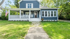 A two-story house with a porch, a front door, and a mailbox. - Three Oaks Unit Steps To Downtown! 2 Night Summer Min! (Three Oaks)