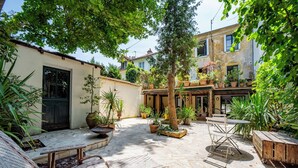 Une cour avec des meubles en osier, des plantes en pot et une table en bois.
