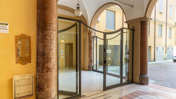 A hotel entrance with glass doors, a revolving door, and a sign indicating the location. - Canalchiaro Suite, 6 guests (Modena)