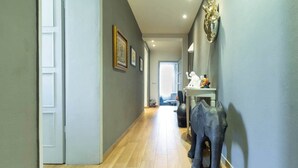 A hallway with a wooden floor, a door on the left, and a wall-mounted elephant sculpture. - Canalchiaro Suite, 6 guests (Modena)