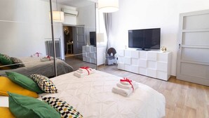 A modern hotel room with a large bed, a television, a mirror, and a wardrobe. - Canalchiaro Suite, 6 guests (Modena)