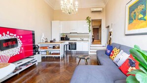 A living room with a flat-screen TV, a grey sofa, and a wooden floor. - Canalchiaro Suite, 6 guests (Modena)