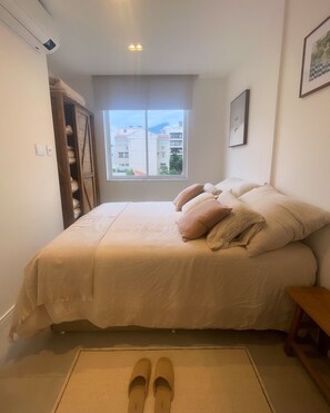 Cozy retreat with a large bed and window offering a view of the surrounding buildings.