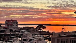 Una marina con imbarcazioni ormeggiate, un edificio sul lungomare e un tramonto sull'acqua.
